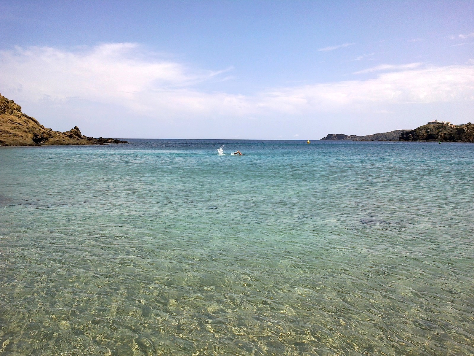 Sa Mesquida Menorca: het dichtstbijzijnde noordkuststrand vanaf Maó 4 Helder, ondiep water voor het strand van Sa Mesquida met zicht op de rotsen van de baai