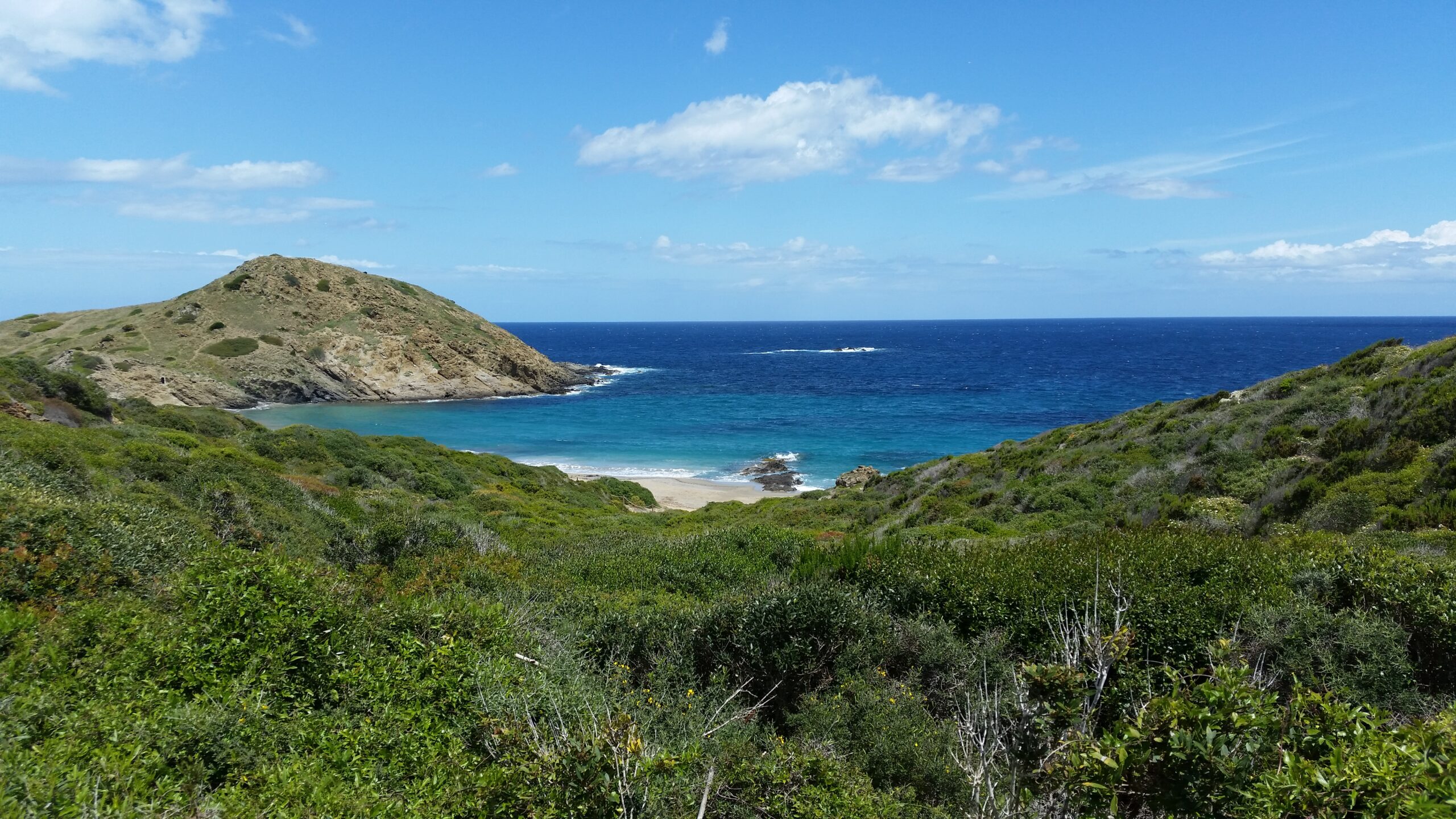 Sa Mesquida Menorca: het dichtstbijzijnde noordkuststrand vanaf Maó 1 Het zandstrand van Sa Mesquida op Menorca met de rotskop Es Pa Gros en blauw water