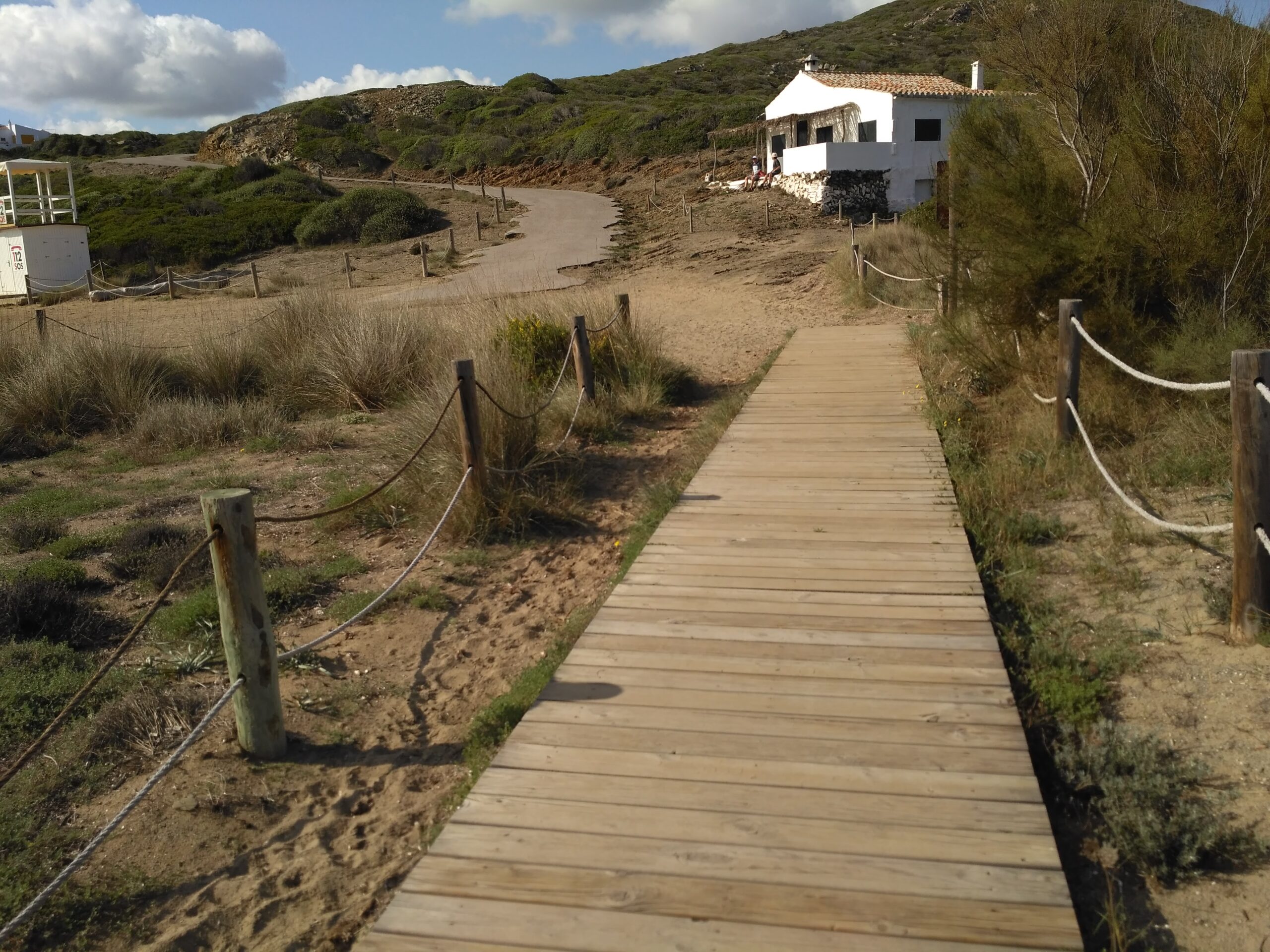 Sa Mesquida Menorca: het dichtstbijzijnde noordkuststrand vanaf Maó 5 Houten vlonderpad over de herstelde duinen achter het strand van Sa Mesquida, onderdeel van het Camí de Cavalls