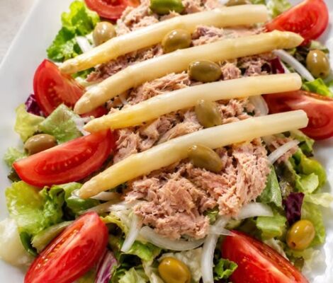 Gemengde salade met tonijn, witte asperges, olijven en tomaat op een wit bord bij Sa Palmera op Formentera