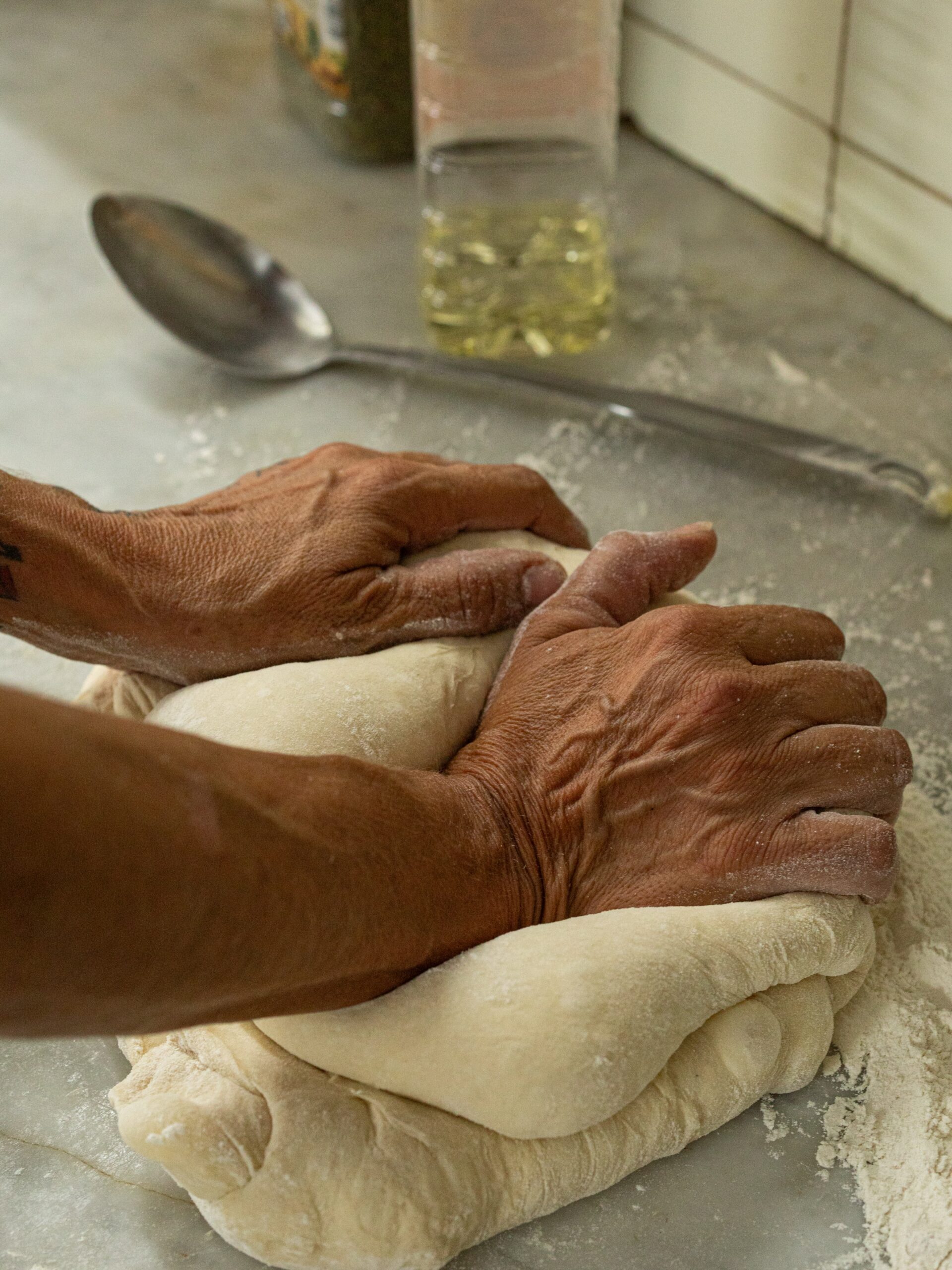 Sa Panxa Formentera: marktkeuken en live muziek in Sant Ferran 1 Handen die pizzadeeg kneden op een bebloemd stalen werkblad in de keuken van Sa Panxa op Formentera