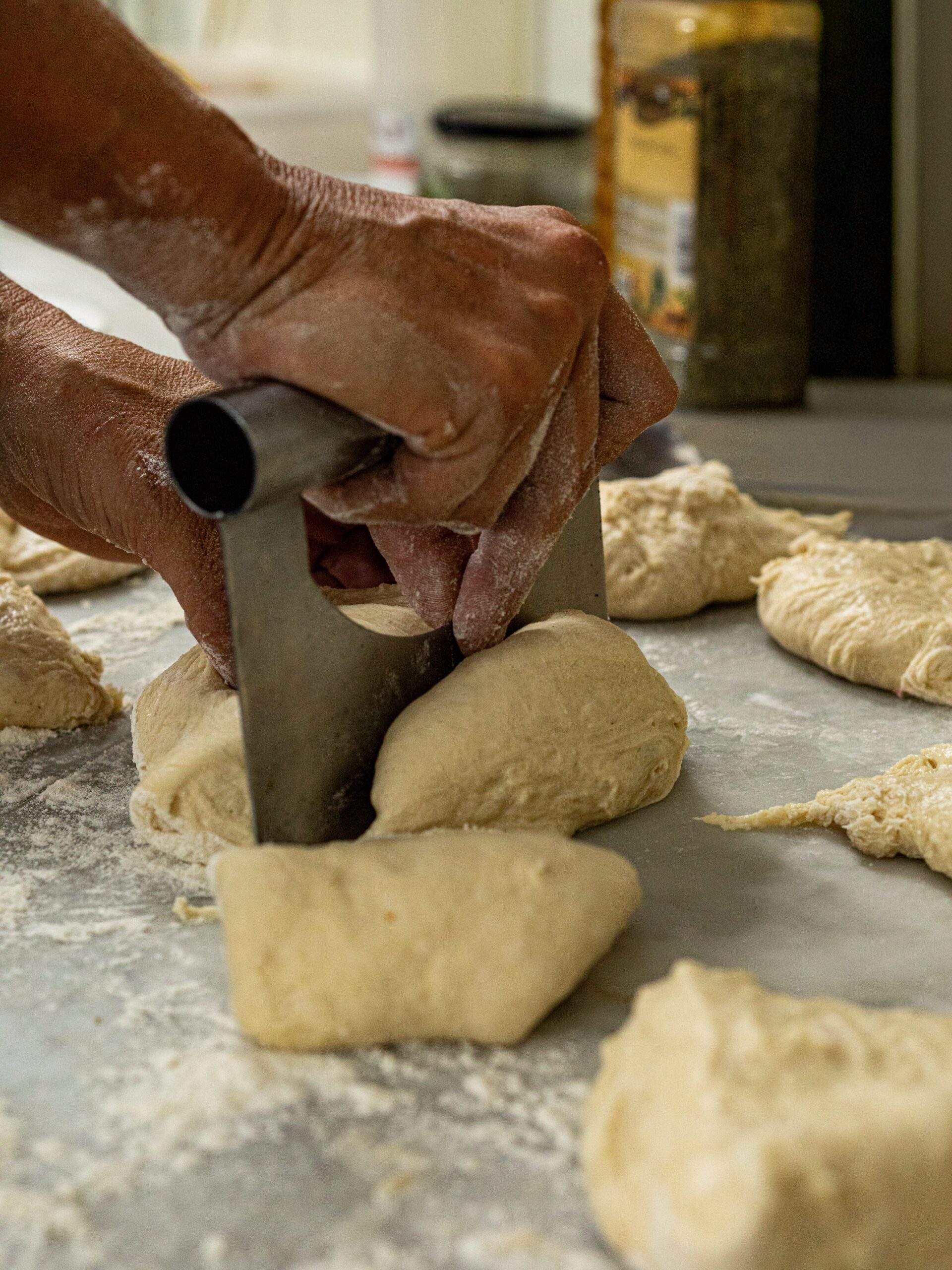 Sa Panxa Formentera: marktkeuken en live muziek in Sant Ferran 2 Een hand portioneert het deeg met een stalen deegsteker, met bollen deeg op het werkblad bij Sa Panxa