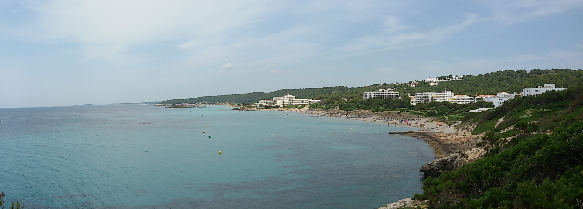 Panorama van de baai van Santo Tomás met het strand en de witte hotels aan de zuidkust van Menorca