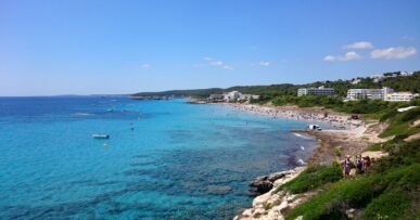 Santo Tomás Menorca: het lange strand dat overgaat in Binigaus 14 De baai van Santo Tomás op Menorca gezien vanaf de Punta de Talis, met turquoise water en de hotels achter het strand