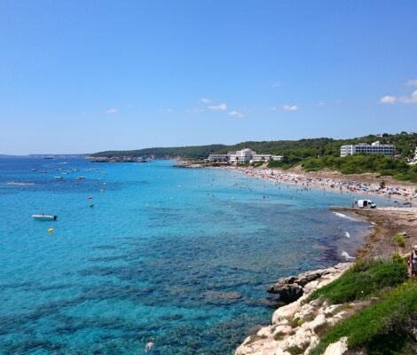 De baai van Santo Tomás op Menorca gezien vanaf de Punta de Talis, met turquoise water en de hotels achter het strand