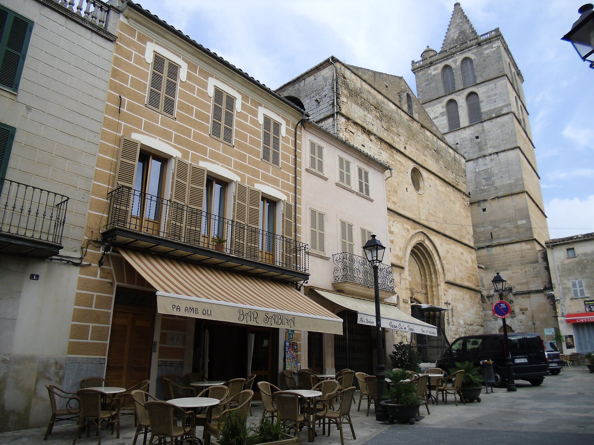 Het kerkplein van Sineu met terrasjes, de gotische gevel van Santa Maria en de losstaande klokkentoren ernaast