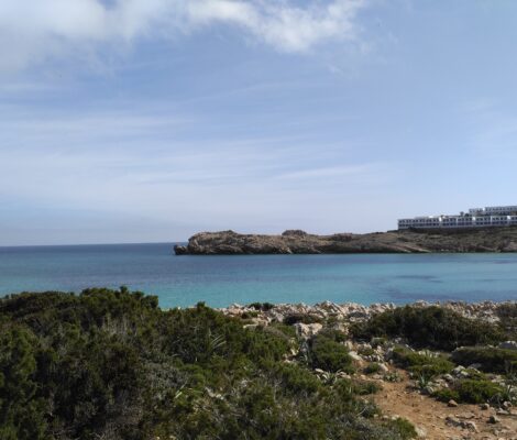 Son Parc Menorca: het duinstrand en de enige golfbaan van het eiland 4 Turquoise water van de baai van Son Parc met de rotskop en de witte appartementen erachter