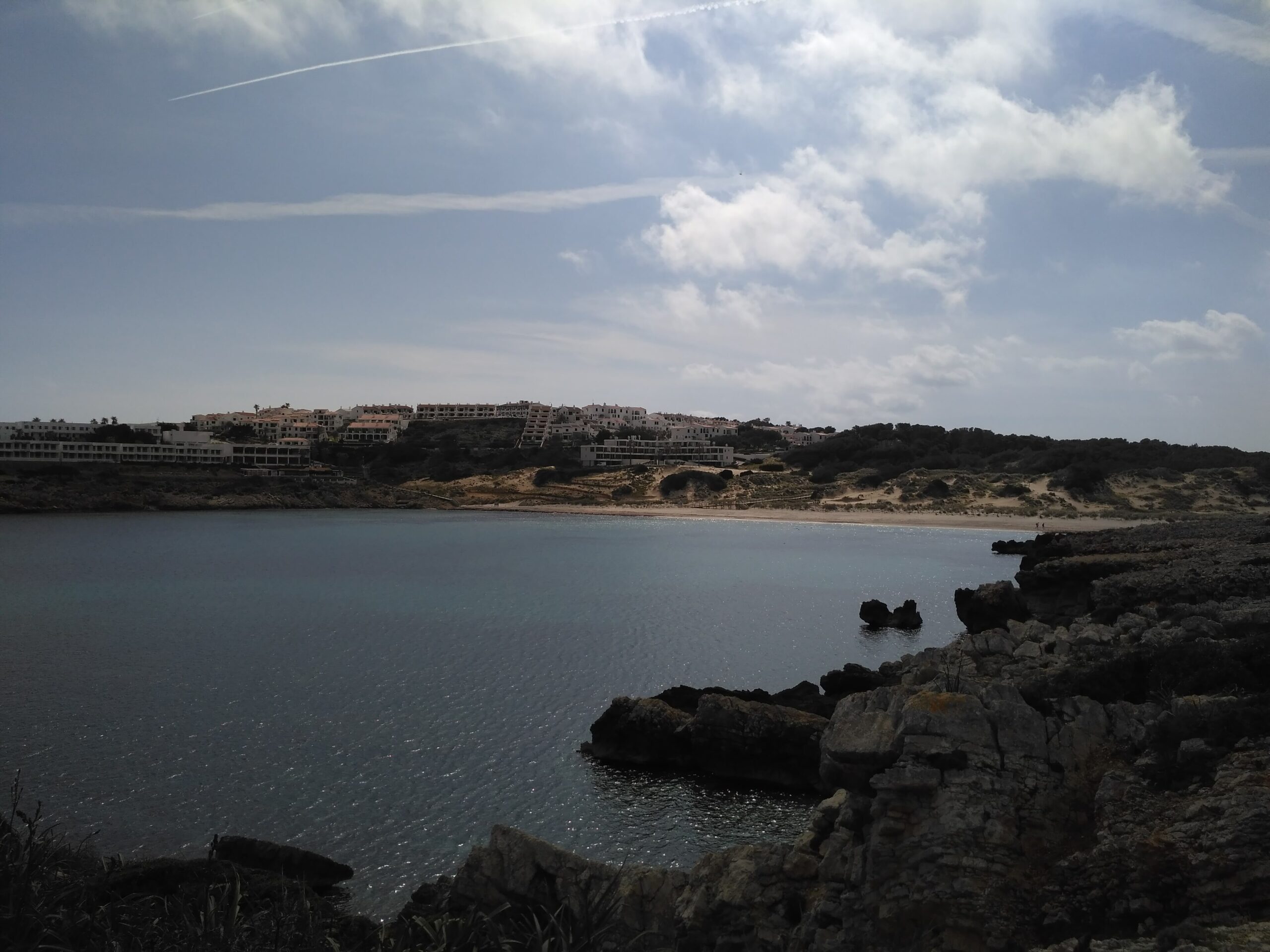 Son Parc Menorca: het duinstrand en de enige golfbaan van het eiland 6 De rotskust bij Son Parc met de bebouwing van de wijk aan de overkant van de baai