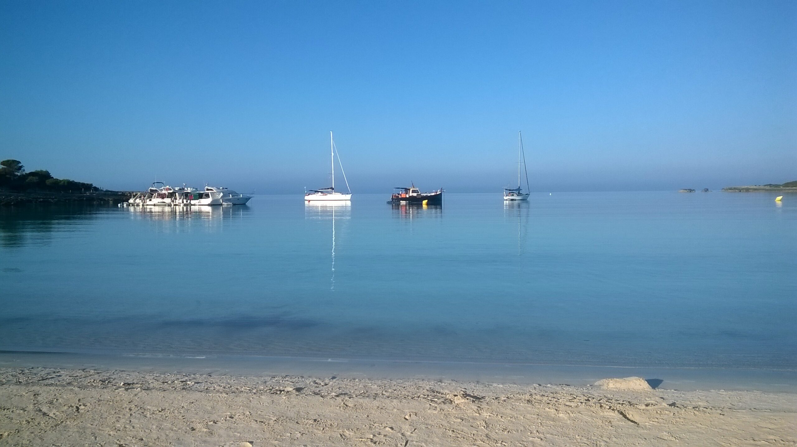 Son Saura Menorca: de dubbelbaai bij Ciutadella, parkeren en bus L66 6 Zeilboten voor anker in het spiegelgladde ondiepe water van de baai van Son Saura