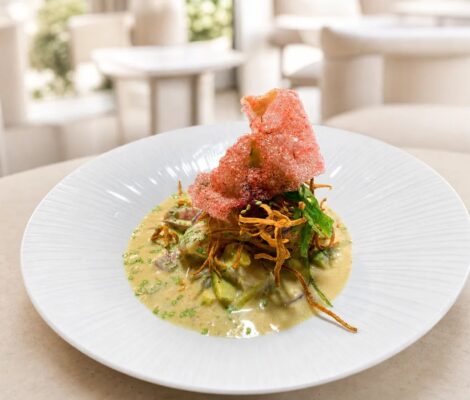 Exotische ceviche van restaurant Sumaq in Palma: vis en avocado in gele leche de tigre op een wit bord, met krokante uitjes en een roze krokantje