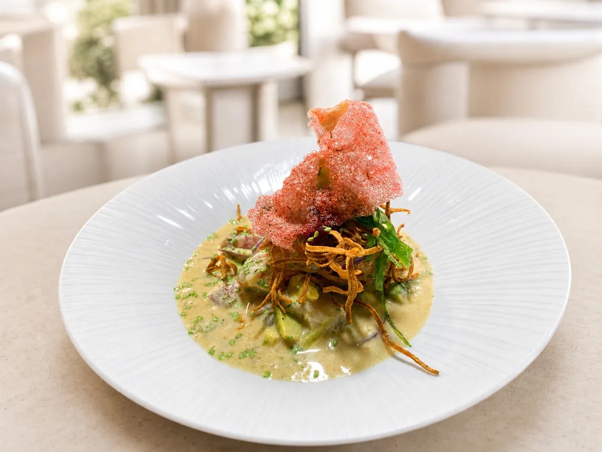 Sumaq Palma: Peruaanse keuken van Irene Gutiérrez in Santa Catalina 1 Exotische ceviche van restaurant Sumaq in Palma: vis en avocado in gele leche de tigre op een wit bord, met krokante uitjes en een roze krokantje