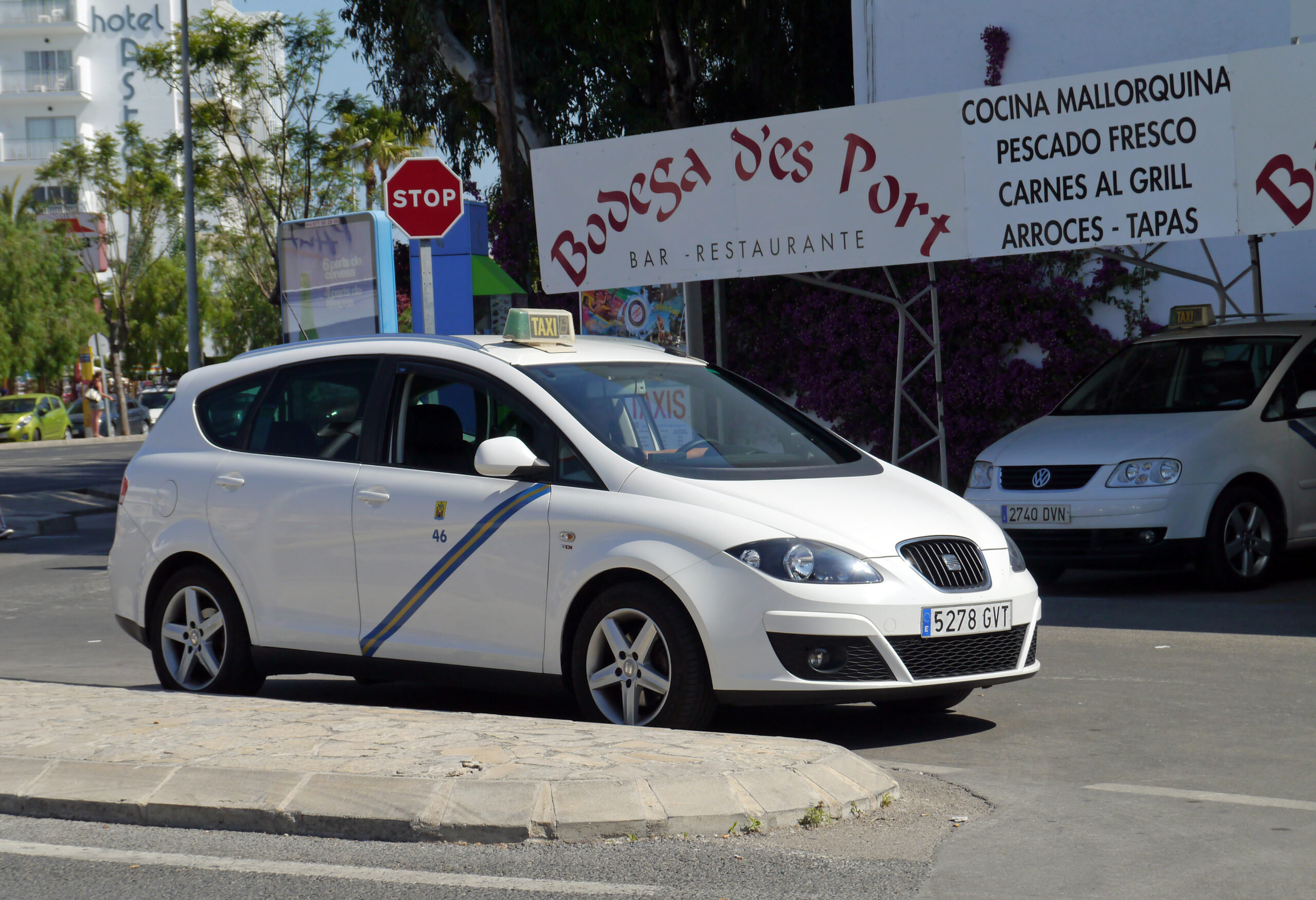 Taxi prijzen Balearen: wat een rit kost per eiland 1 Witte taxi met groene schuine streep op het portier bij een standplaats in Port d'Alcúdia op Mallorca