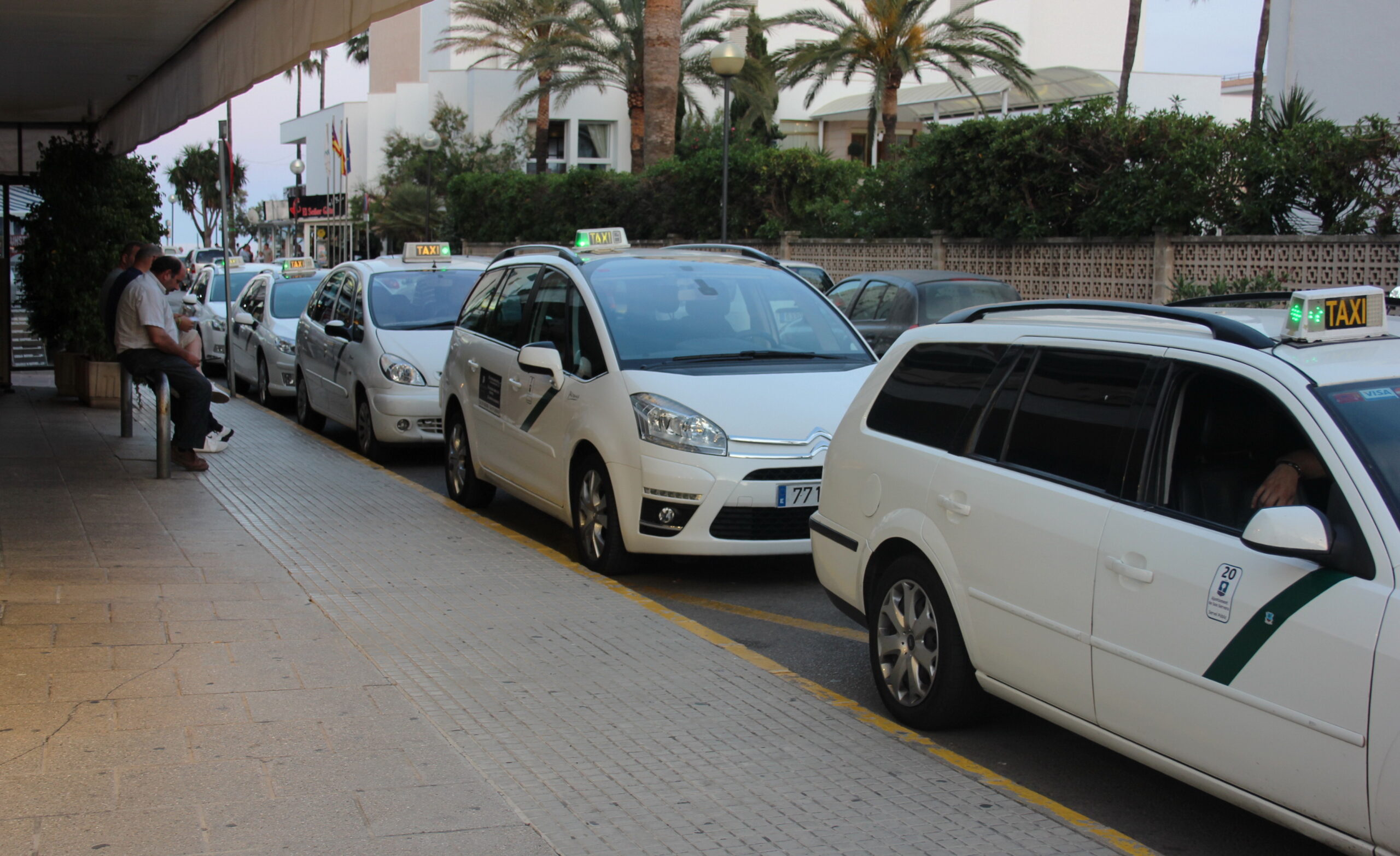 Rij witte taxi's bij de standplaats in Cala Millor op Mallorca, met het taxibordje op het dak
