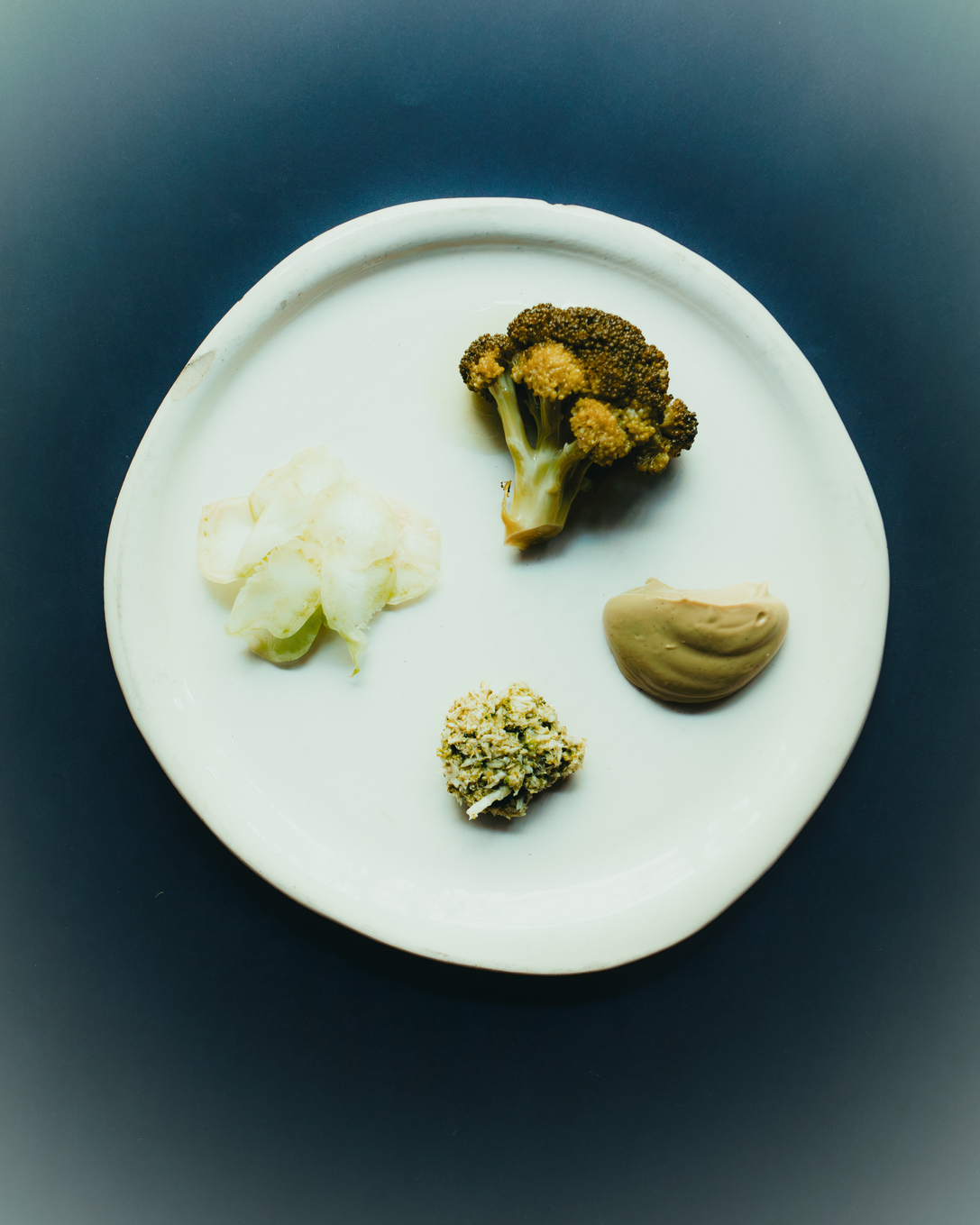 Bord van Terrae met broccoli, bloemkool en twee groene crèmes op wit aardewerk